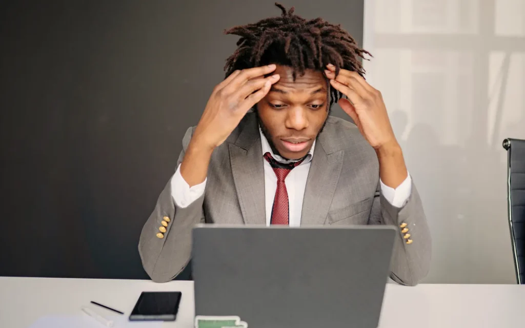 Mold-toxicity-symptoms-in-office A man in a suit with head in hands struggling to concentrate, representing mold toxicity symptoms in an office environment